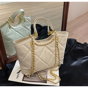 Close-up of beige quilted tote bag with large diamond stitching and gold chain strap
