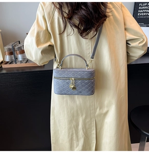 Detail of grey box crossbody bag with diamond stitching and golden chain pendants