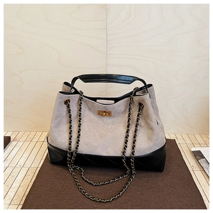 Detail of grey suede tote bag with diamond quilting and gold twist-lock closure