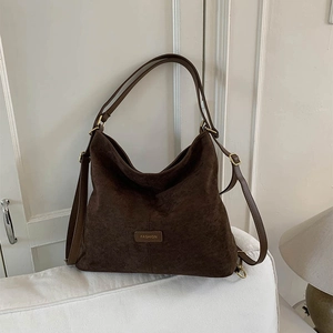 Macro shot of dark brown suede bag detail with FASHION patch and leather strap texture