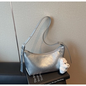 Detail of silver metallic hobo bag with pleated texture and plush puppy charm