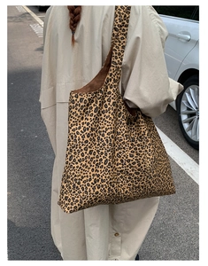Detailed view of a leopard print tote bag worn on shoulder in an urban street setting