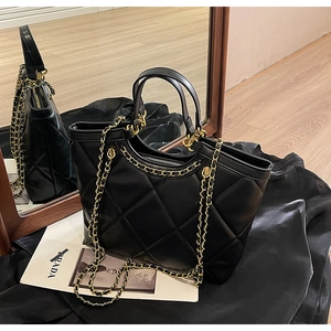 Close-up of black quilted tote bag with gold chain strap and detailed PU leather texture