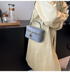 Detailed view of grey-blue quilted vanity bag featuring gold zipper and long shoulder strap