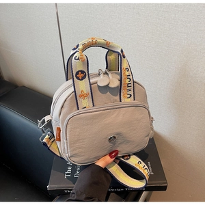 Detail einer grauen Nylon-Handtasche mit gewebtem Tragegriff und Reißverschlussfächern