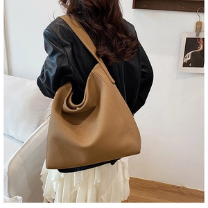 Detailed view of the large brown leather hobo tote bag texture on model's shoulder