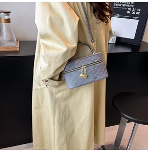 Gray quilted box crossbody bag featuring gold zippers and a refined top handle detail