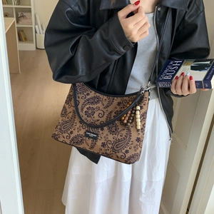Détail d'un sac sous le bras à motif cachemire marron avec perles en bois et étiquette logo