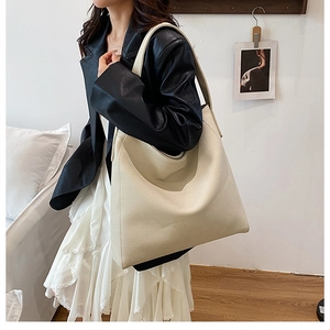 Detail view of beige large capacity faux leather tote bag with lychee texture and wide strap