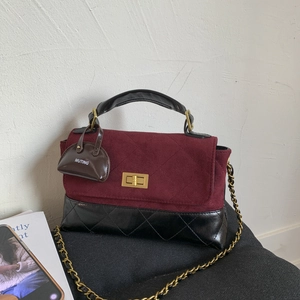 Detail of burgundy and black quilted handbag with gold clasp and chain strap