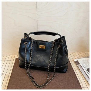 Detail of black quilted leather tote bag with gold metal twist lock and chain strap