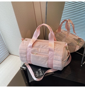 Pink quilted cylindrical travel bag with adjustable strap and golden hardware details
