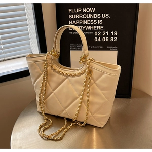 Macro detail of beige quilted tote bag featuring classic diamond stitching and gold chain strap