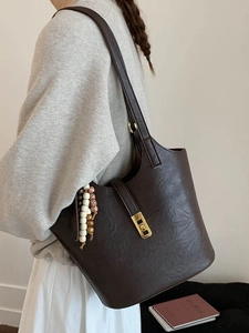 Retro dark brown leather bucket bag with gold clasp and ethnic beaded charm for women
