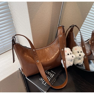 Detail of vintage brown leather underarm bag with pleated texture and plush puppy charm