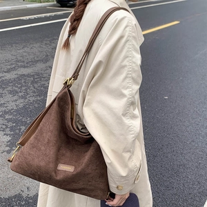 Detail of vintage brown suede tote bag with adjustable strap worn on beige coat