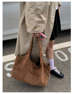 Close-up of brown suede tote bag featuring leopard print lining and functional front pocket