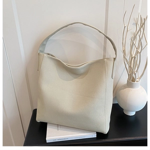 Close-up of minimalist beige hobo tote bag with wide strap and textured synthetic leather