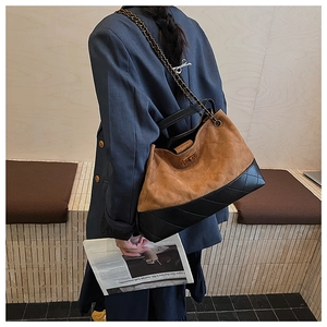 Detail of vintage tote bag with quilted suede panel, chain strap, and turn-lock closure