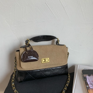 Detail of a chic chain handbag featuring khaki suede and black diamond quilted leather