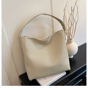 Detail of minimalist cream leather tote bag showing grainy texture and hobo design