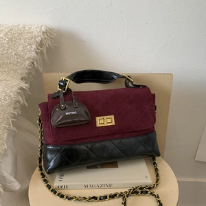 Detail of burgundy suede and black quilted leather crossbody bag with gold turn-lock