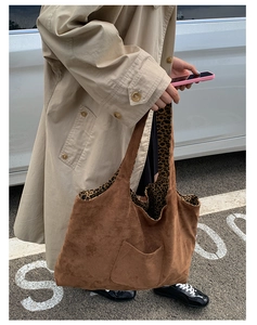 Close-up of brown suede tote bag with leopard print lining worn with a trench coat
