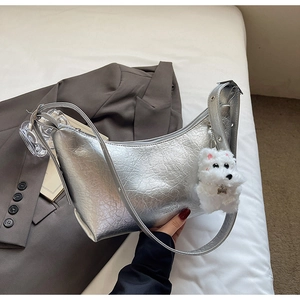 Silver metallic hobo bag with crackle texture and white plush puppy charm on a blazer