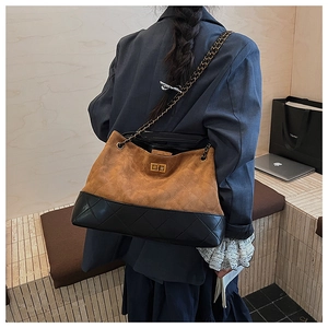 Detail of hobo bag featuring brown suede and black quilted leather with chain strap