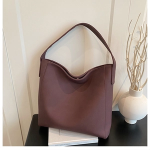 Detail view of large dark brown hobo tote bag with matte texture on a minimalist desk