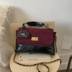 Close-up of contrast quilt flap bag with gold twist lock and designer bag charm