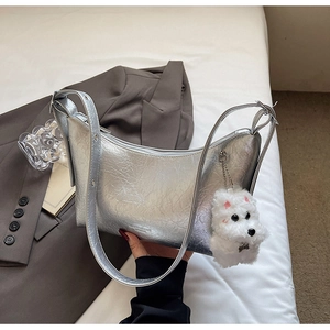 Detail of silver metallic crescent bag with wrinkled texture and plush puppy charm