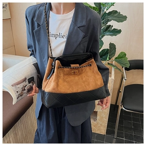 Detail of two-tone bucket bag with brown suede, black quilted leather and gold clasp
