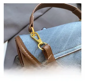 Detail shot of the premium golden metal hook on a blue denim bag with leather trim