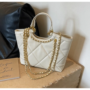 Close-up of white quilted tote bag featuring golden chain detail and diamond pattern texture