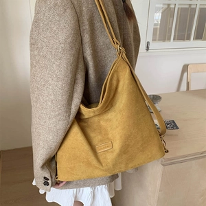 Detail of ginger suede tote bag with metal buckle and fashion logo on model