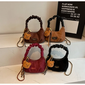 Detail of ruched handles and bear charms on four velvet half-moon shoulder bags
