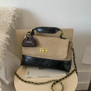 Detailed shot of beige suede and black quilted leather handbag with gold twist lock