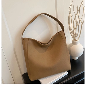 Detail of camel brown large tote bag on black wooden table with artistic minimalist decor