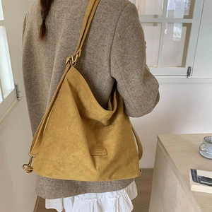 Close-up of ginger yellow suede tote bag with FASHION leather label and gold hardware