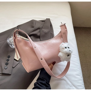 Pink crescent shoulder bag with pleated faux leather texture and plush dog pendant charm