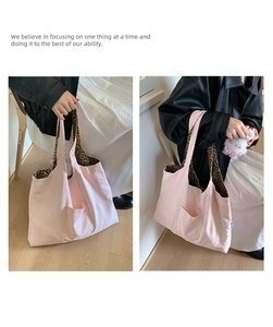 Detail of pink canvas tote bag featuring leopard print handles and outer pocket detail