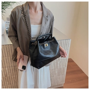 Detail of black quilted leather tote bag featuring gold chain strap and rotary lock buckle