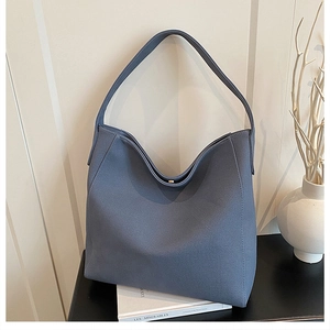 Detail of grey-blue matte tote bag featuring a gold magnetic closure and premium texture