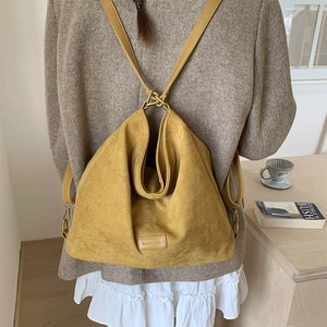 Detail view of mustard yellow suede backpack with foldable top and elegant leather straps