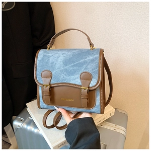 Detail of blue denim and brown leather contrast stitching on the luxury crossbody bag