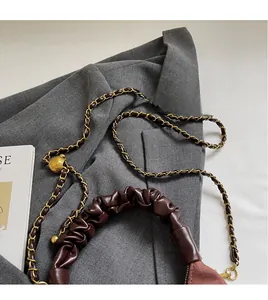 Detailed close-up of brown leather bag with golden chain strap and ball adjuster