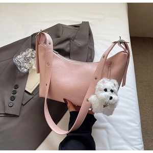 Pink patent leather shoulder bag detail with wide strap and plush dog charm