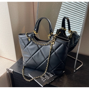 Detail showing the quilted diamond pattern and golden chain on black leather tote bag