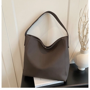Detail view of deep brown matte PU leather tote bag against a minimalist studio background